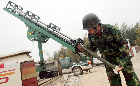 חייל סיני מתכונן לשגר רקטה שתזריע עננים ותגרום לגשמים